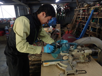 真剣な表情で丸太をスライスする小池保護官